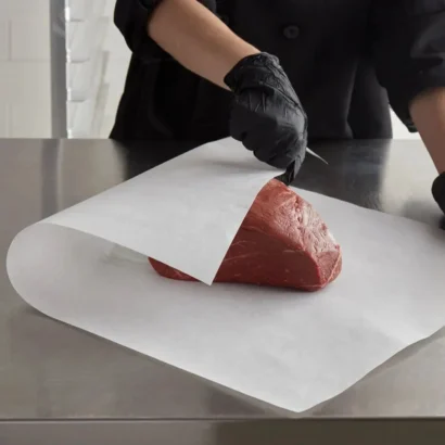 A person wrapping a large beef roast cut in food-grade white butcher paper