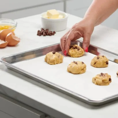 Chocolate chip cookie dough placed on a baking sheet lined with custom non-stick baking parchment